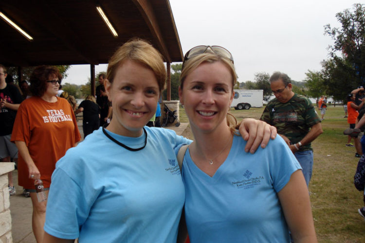 Two women in blue shirts posing for a picture.