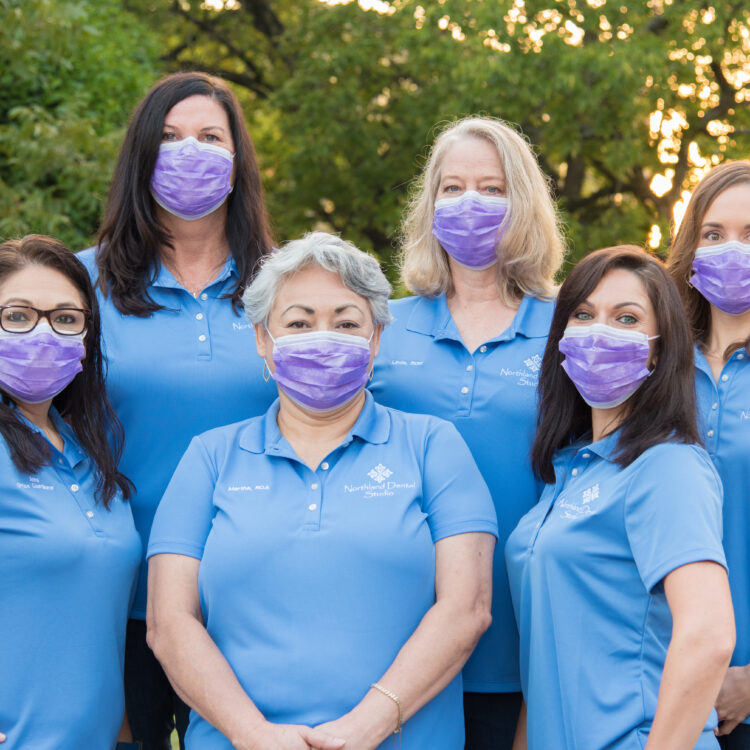 A group of women wearing blue shirts and masks.